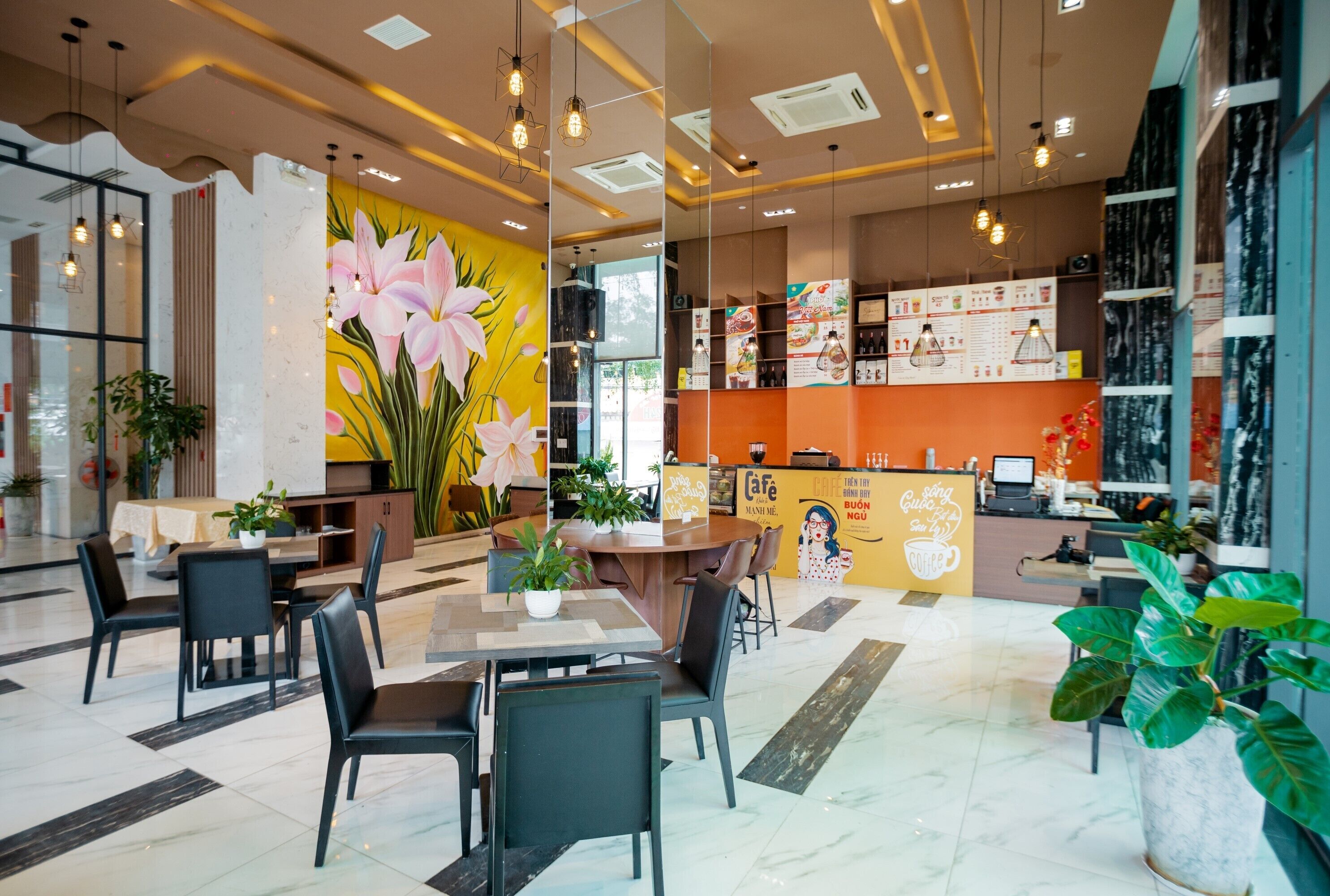A modern cafe interior with a large floral mural, a counter with menu boards, and seating arrangements.