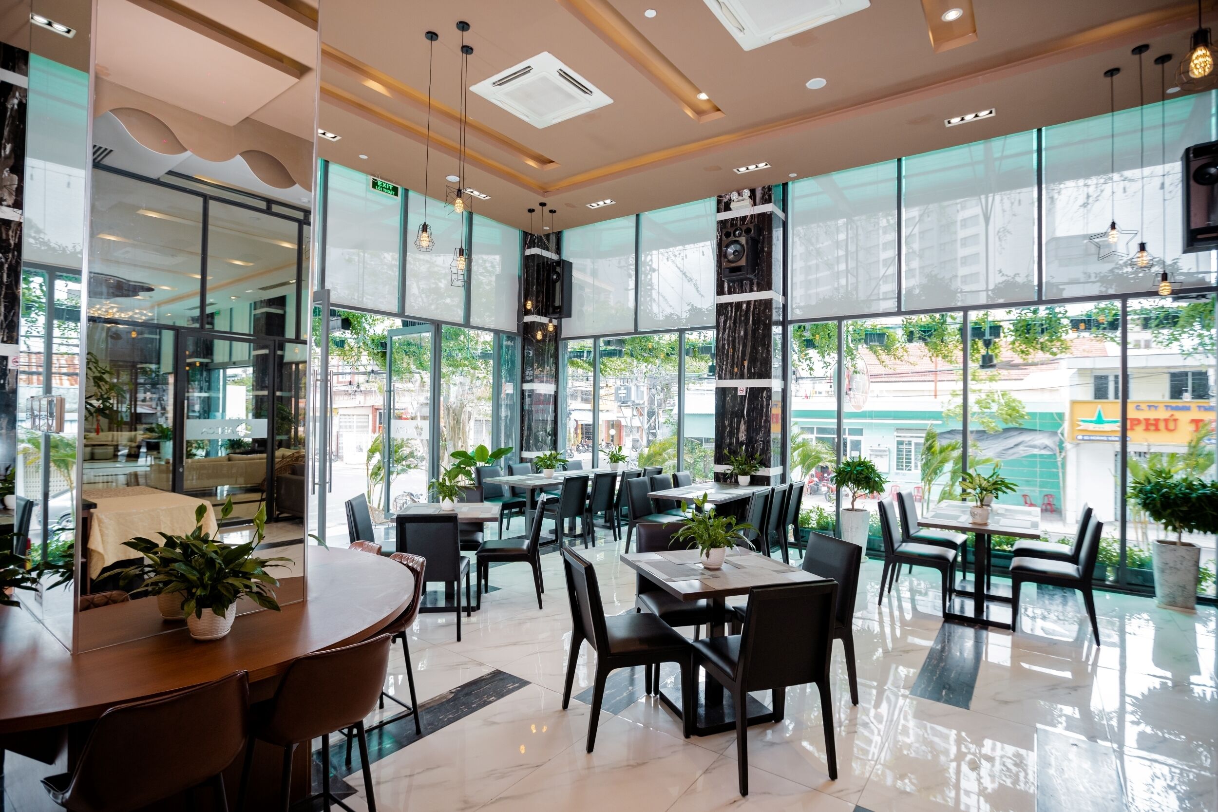 Un café moderne doté de grandes fenêtres, de plantes d’intérieur et d’un aménagement épuré et contemporain.