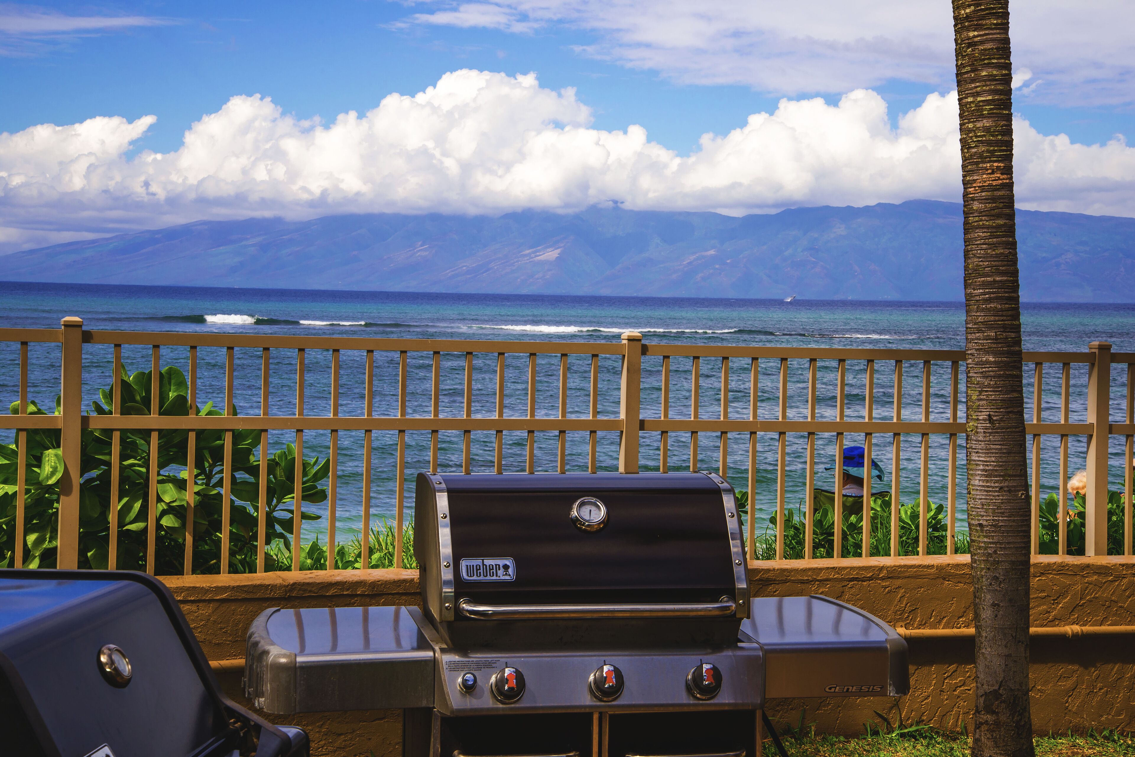 A barbecue grill with a view of the ocean and mountains in the background.