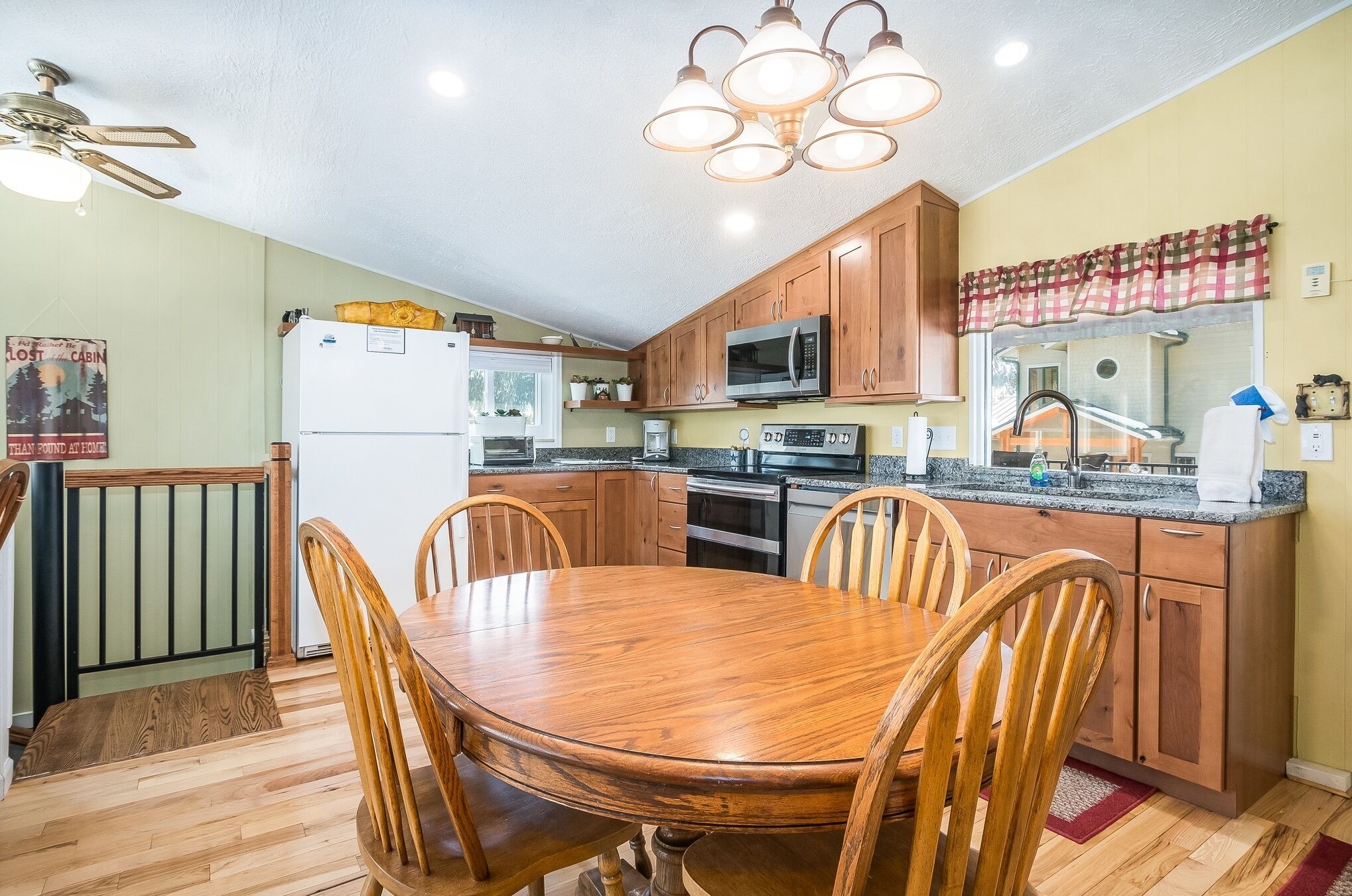 Una cocina con armarios de madera, microondas, refrigerador y una mesa de comedor con sillas.