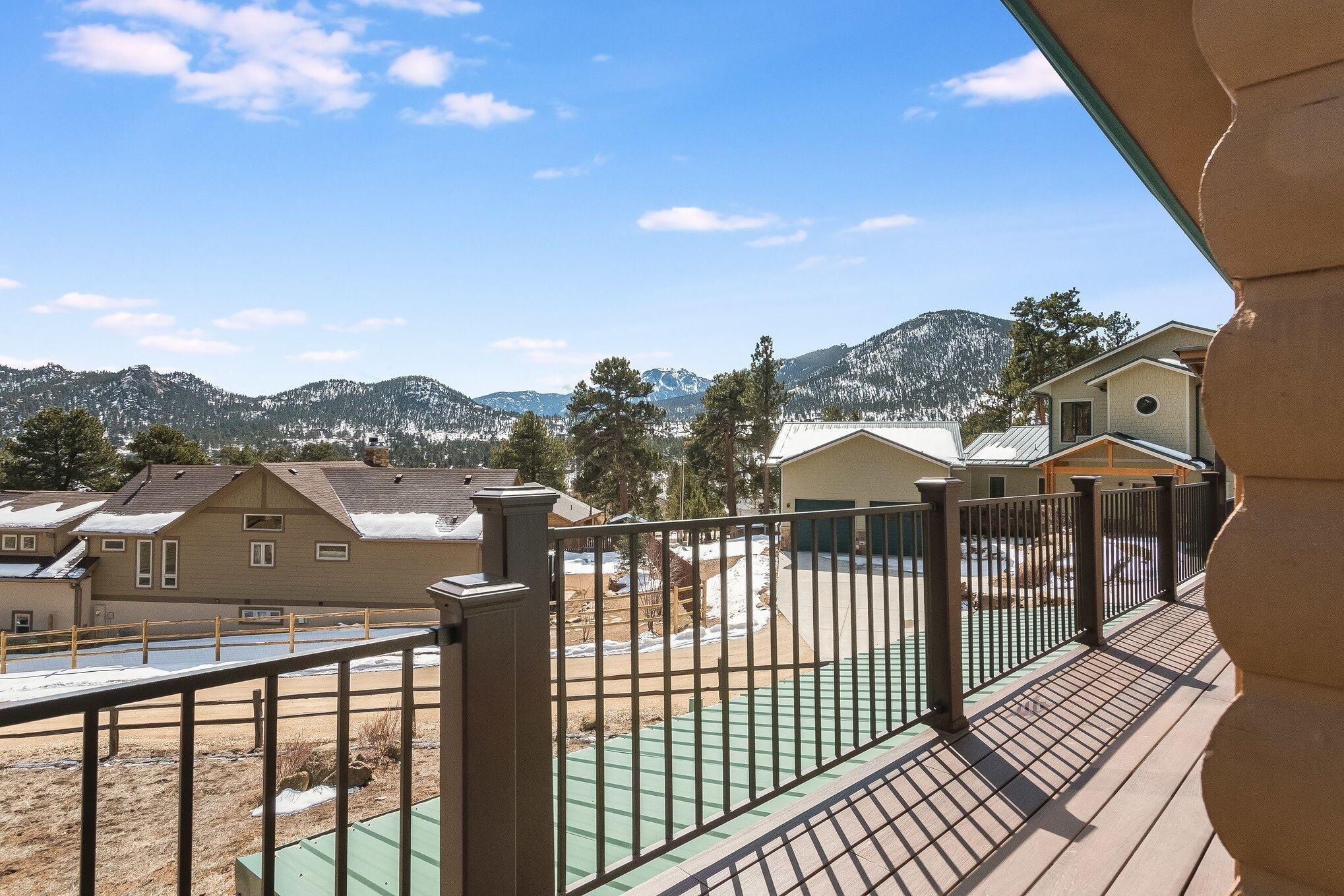 Zona residencial con casas, un parque infantil vallado y montañas al fondo.