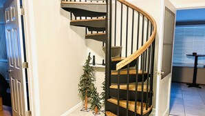 A modern spiral staircase with wooden steps and black railings, a small artificial Christmas tree, and a door leading to another room. - Starlight In The Rockies Ev #3172 3 Bedroom Home by RedAwning (Estes Park)