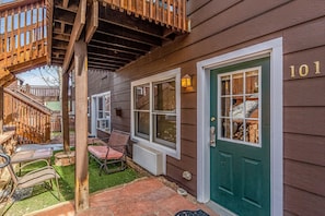 Une maison en bois avec une porte verte, le numéro 101, et une véranda couverte avec des chaises et une table.