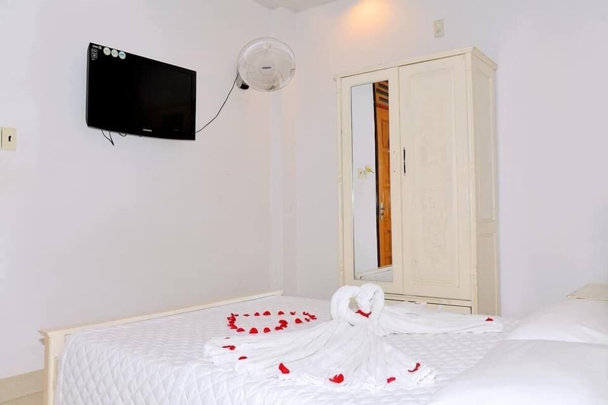 A hotel room with a bed, a television mounted on the wall, and a wardrobe.