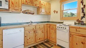 Una cocina con armarios de madera, un microondas, una estufa y un lavavajillas.