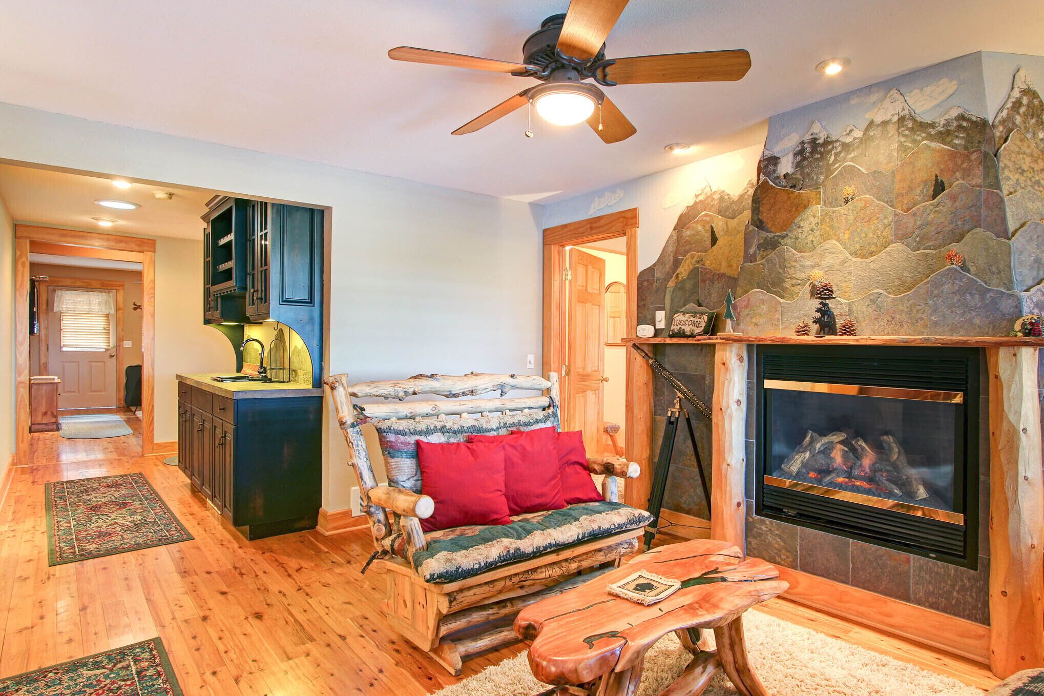A cozy living room with a fireplace, wooden furniture, and a stone accent wall.