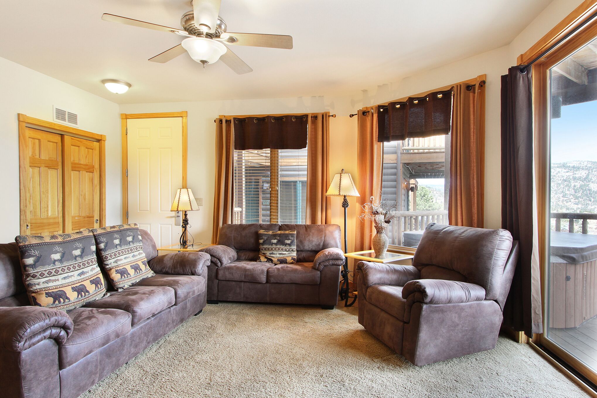 A living room with a brown leather sofa set, a brown leather armchair, and a small side table with a lamp.