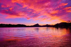 Un lago al atardecer, con montañas al fondo y un cielo despejado.