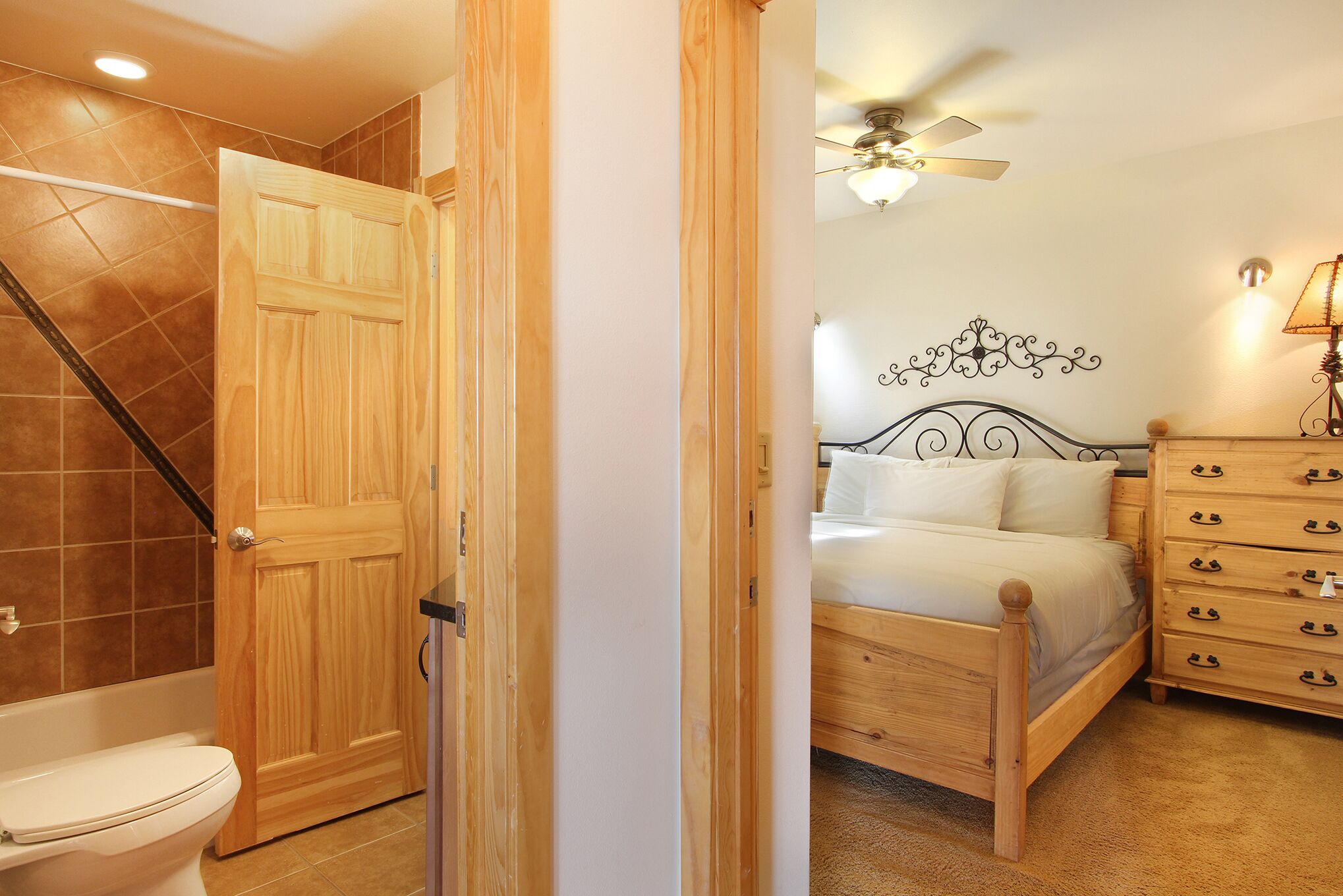 A bedroom with a wooden bed, a nightstand, a dresser, and a ceiling fan.