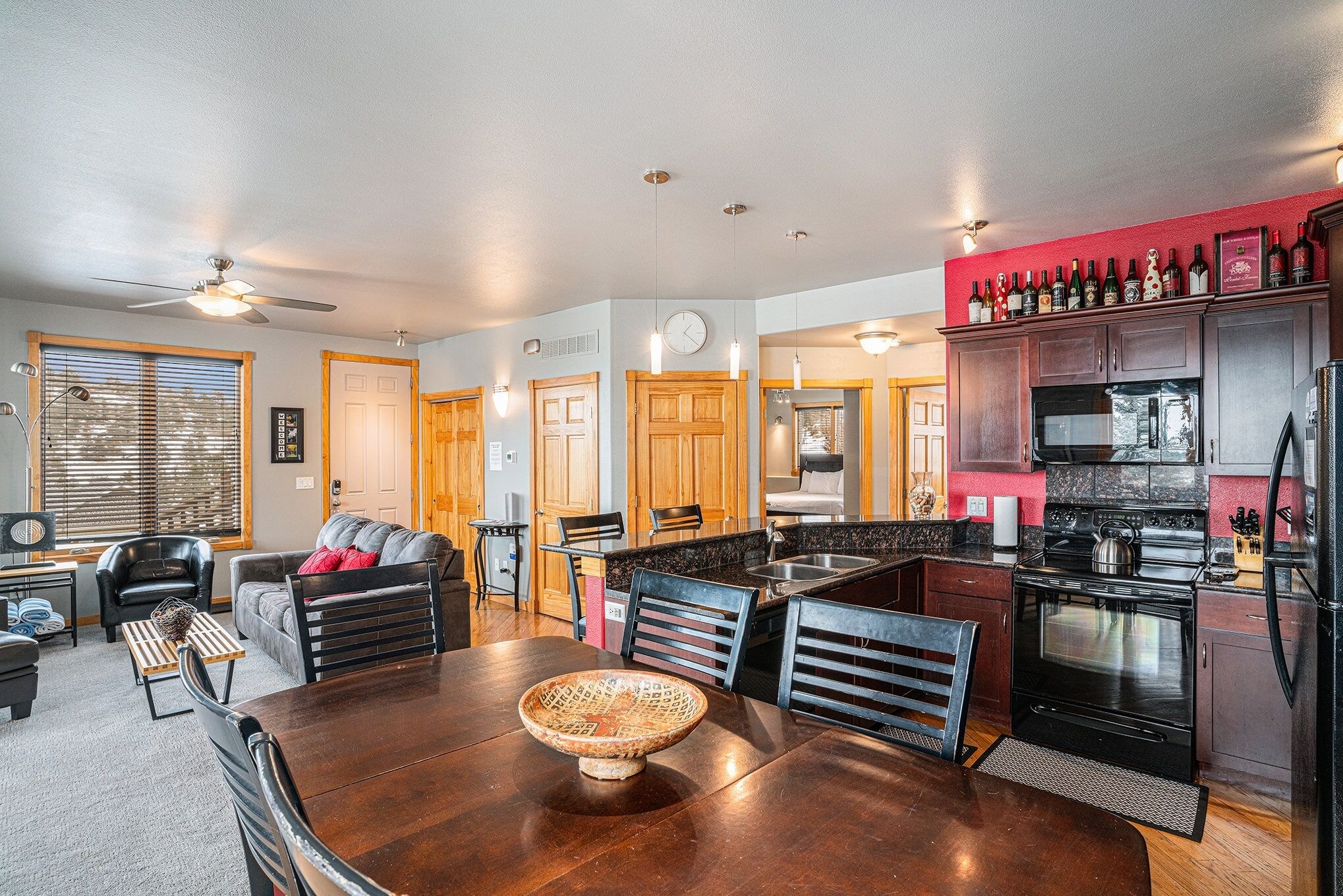A modern kitchen with a dining area, wooden cabinets, and a variety of appliances.