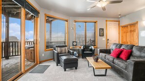 A cozy living room with a fireplace, comfortable seating, and large windows. - Nakai Peak 41b 2 Bedroom Condo by RedAwning (Estes Park)