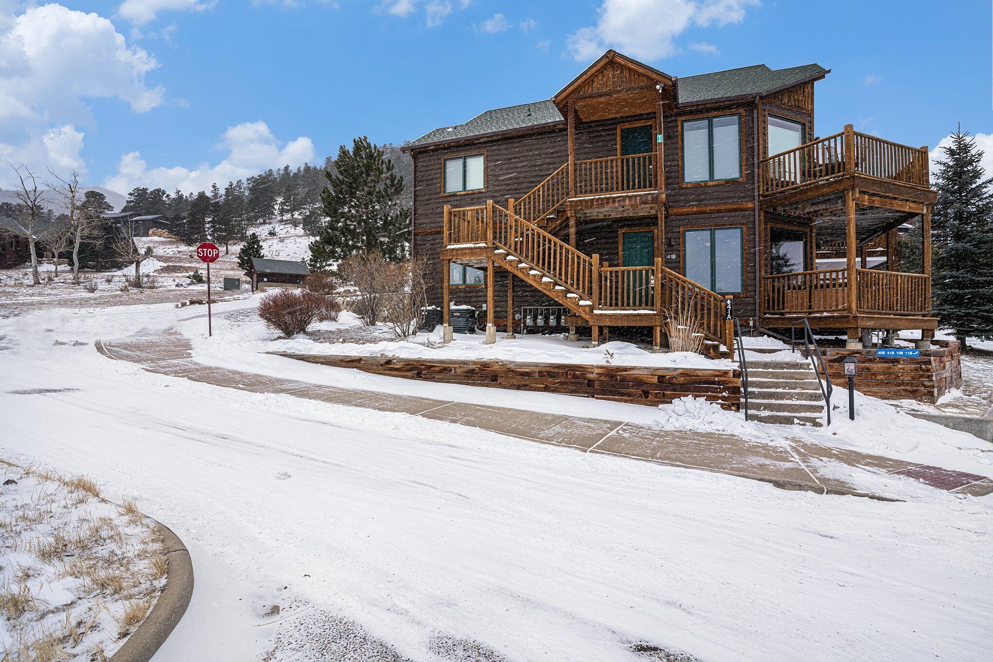 A two-story wooden cabin with a balcony and a staircase leading to the upper level.