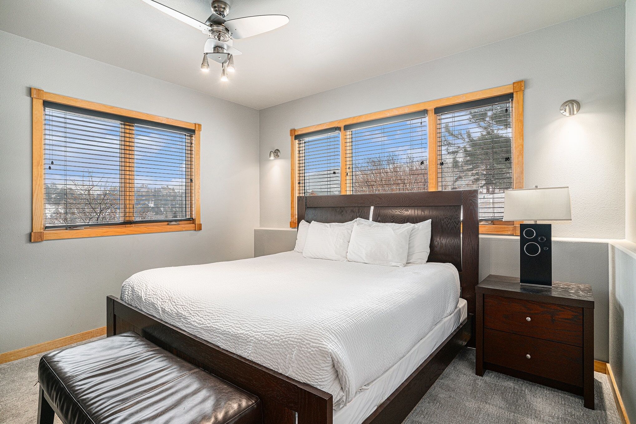 A bedroom with a large bed, wooden headboard, two bedside tables with lamps, and a bench.