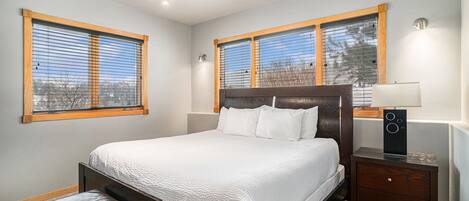 A bedroom with a large bed, wooden headboard, two bedside tables with lamps, and a bench.