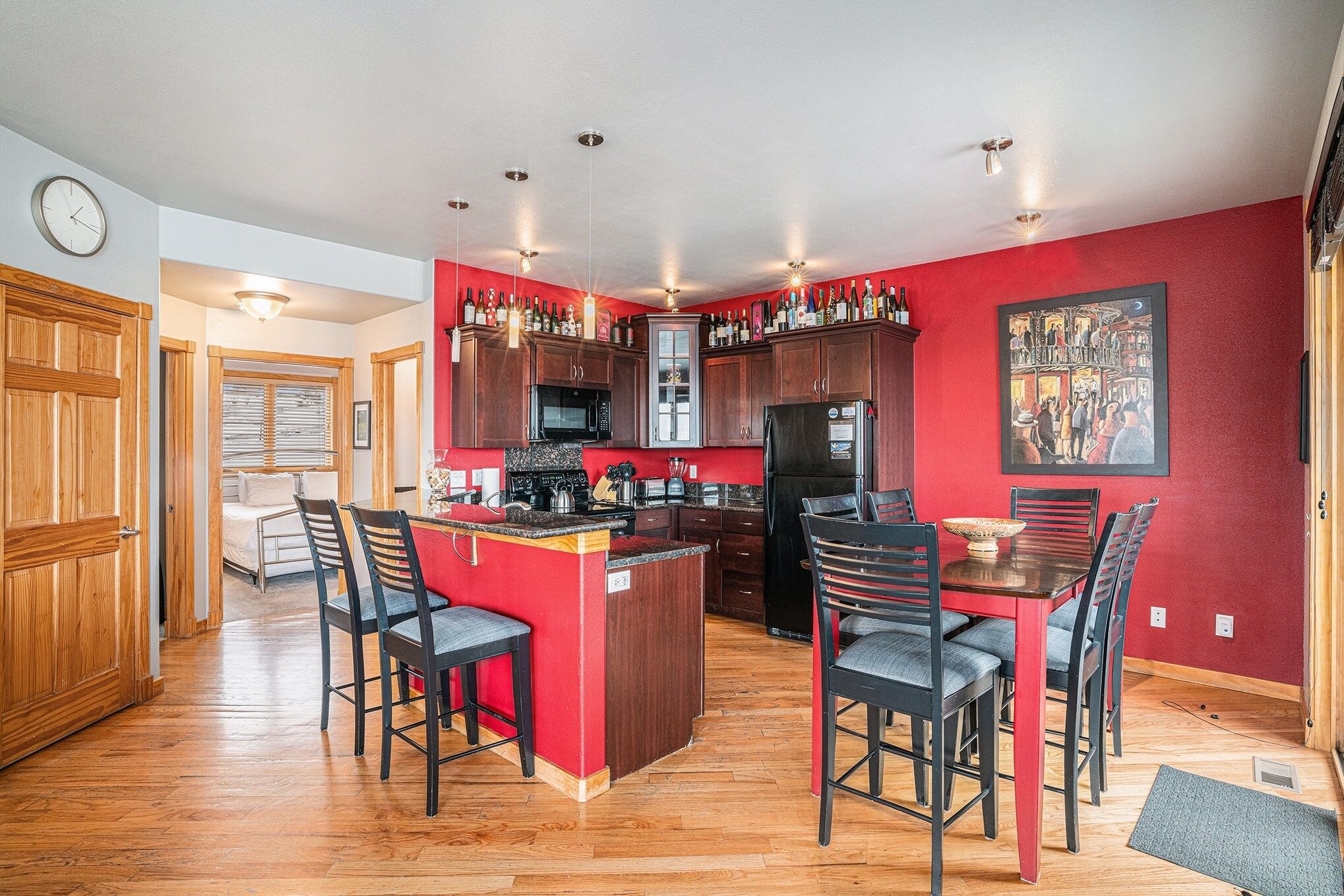 A modern kitchen with wooden cabinets, a central island, and a dining area with chairs.