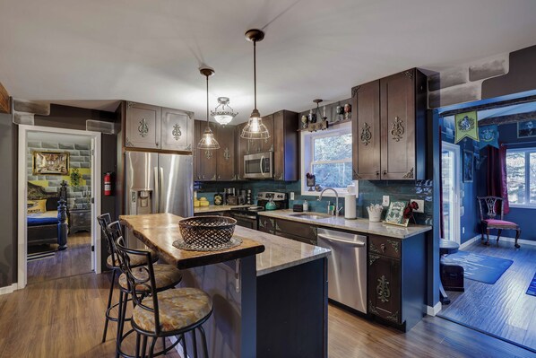 A modern kitchen with dark wood cabinets, stainless steel appliances, and pendant lighting.