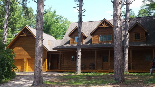A log cabin with a central porch and multiple windows.