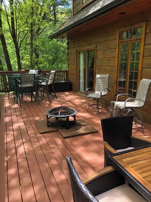 Une terrasse en bois avec des meubles d’extérieur, notamment des chaises et une table, ainsi qu’un foyer.