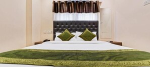 A hotel room with a large bed, a headboard, two pillows, a nightstand, and a window with curtains. - Treebo Trend Royal Crowne (Barakpur)
