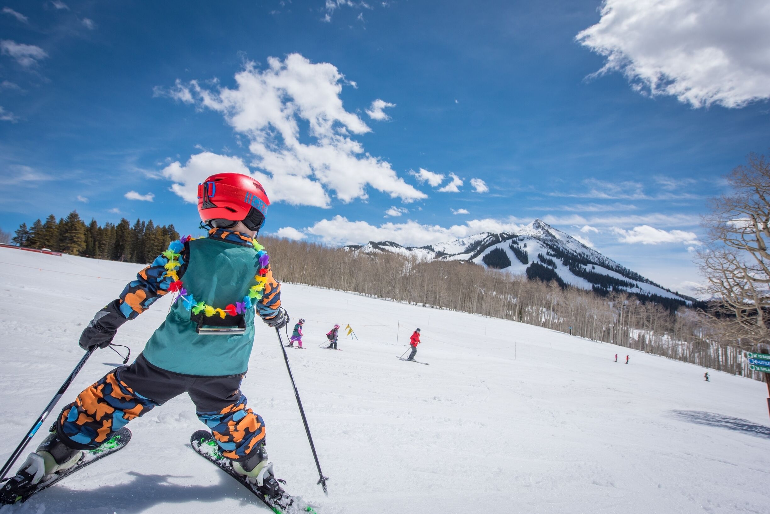 A person skiing on a snowy slope with a mountain in the background.