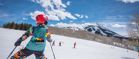 A person skiing on a snowy slope with a mountain in the background.