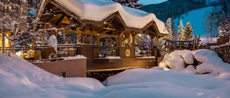 A snow-covered wooden structure with a sign reading "Transfertsur VISITING" and a logo.