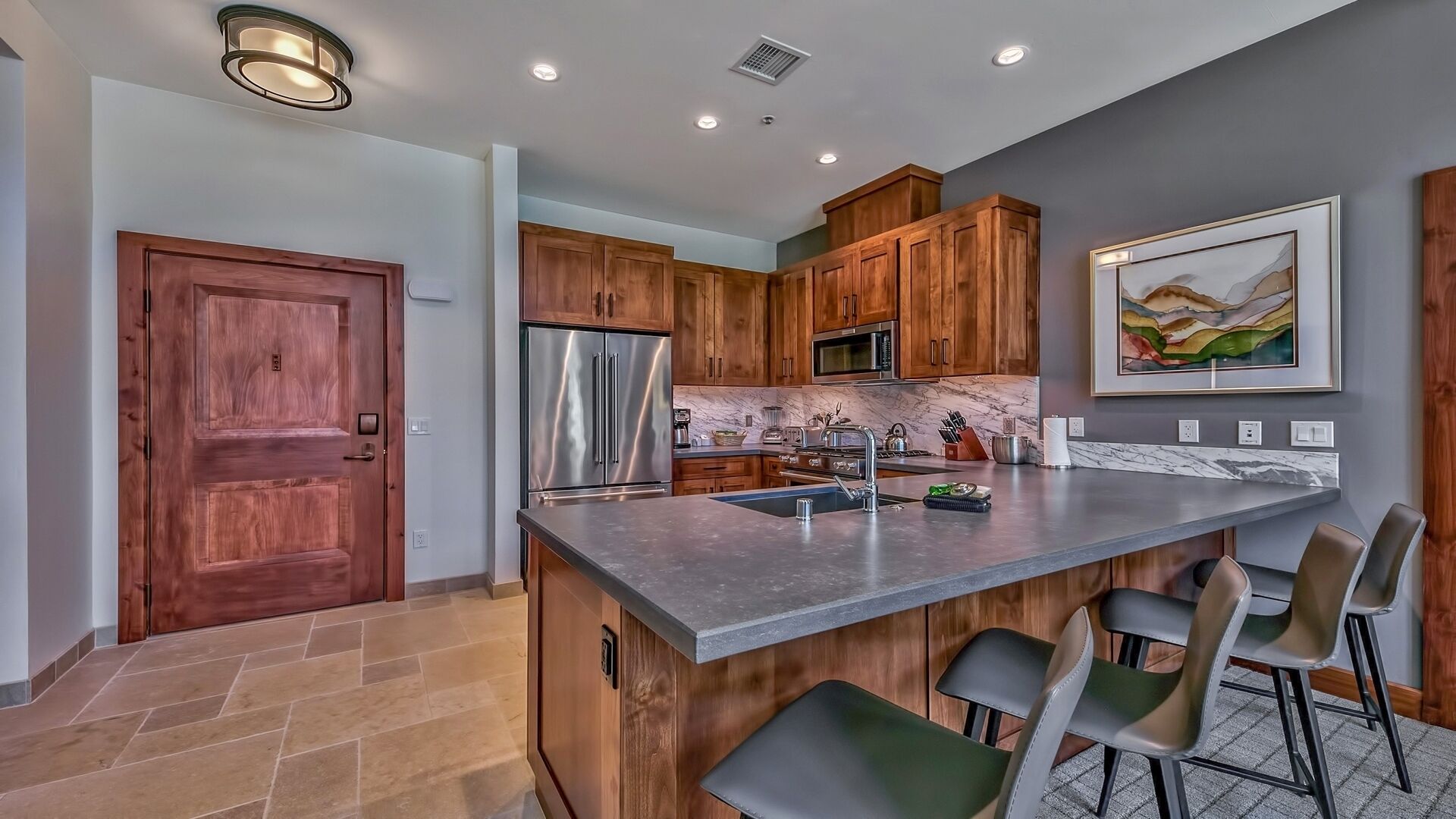 A modern kitchen with wooden cabinets, stainless steel appliances, and a marble countertop.