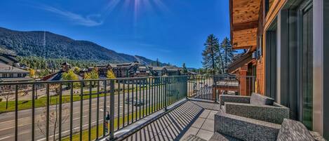A balcony with a view of a mountain, a road, and buildings.