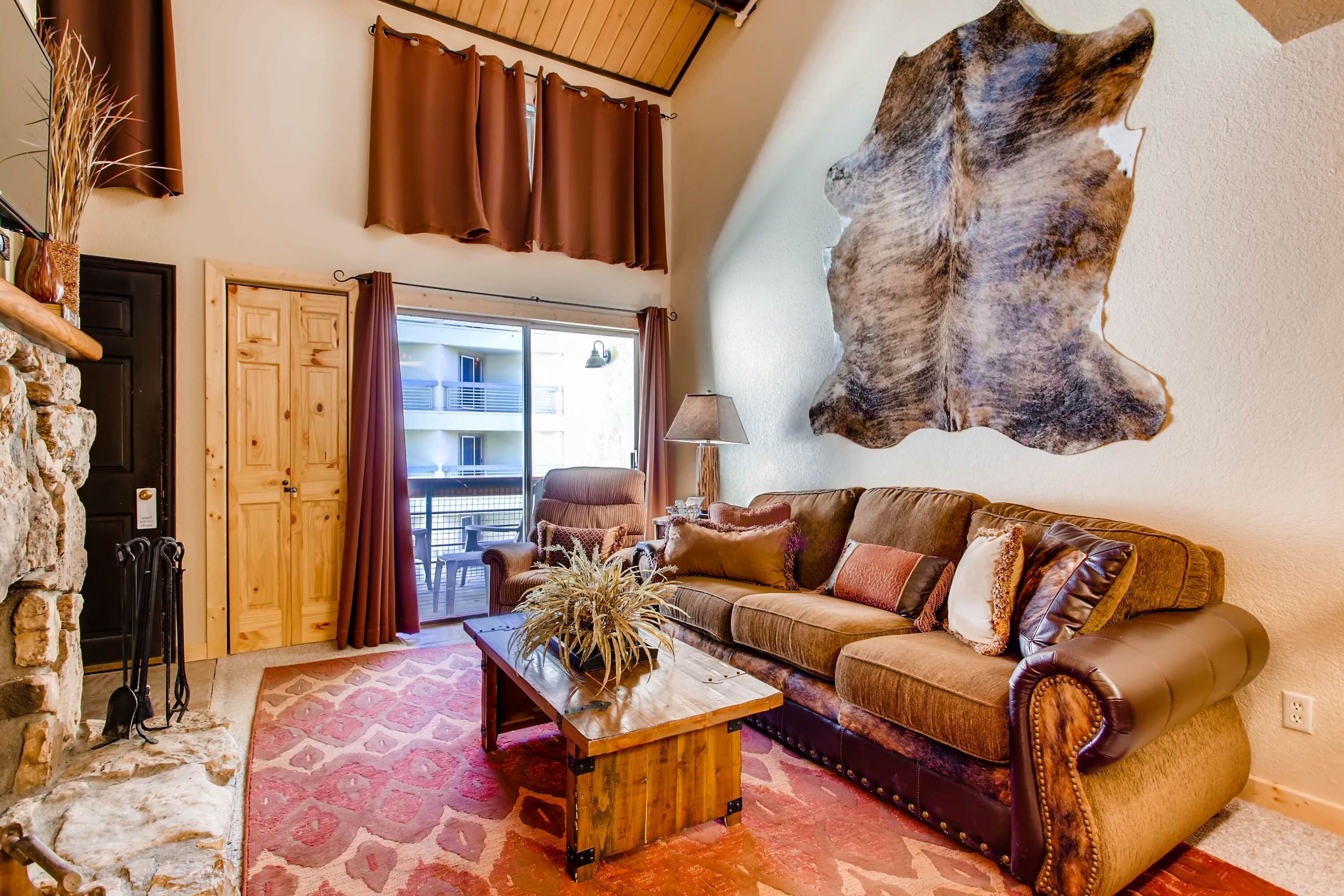 A cozy living room with a leather sofa, a wooden coffee table, and a large fur rug.
