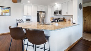 A modern kitchen with white cabinets, stainless steel appliances, and a granite countertop.