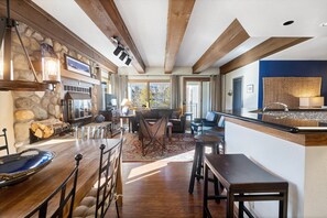Une cuisine spacieuse avec un bar en bois, un mur en pierre et de grandes fenêtres.