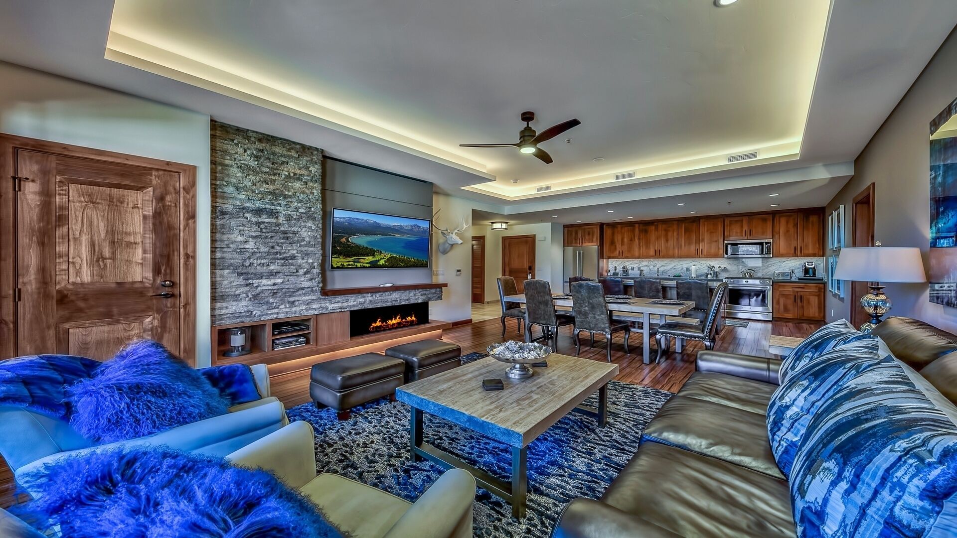 A modern living room with a fireplace, a dining area, and a kitchen.