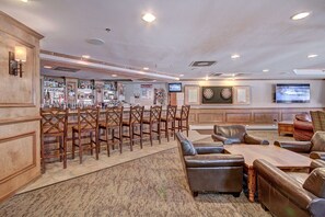 A bar area with wooden chairs and a bar counter, a seating area with leather sofas, and a dartboard on the wall. - Spacious  In The Heart Of Breckenridge Studio Condo by RedAwning (Breckenridge)