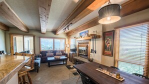 A spacious living area with a wooden dining table, a sofa, and a fireplace. - Lovely Modern Plaza Condo - No Cleaning Fee! by RedAwning (Crested Butte)