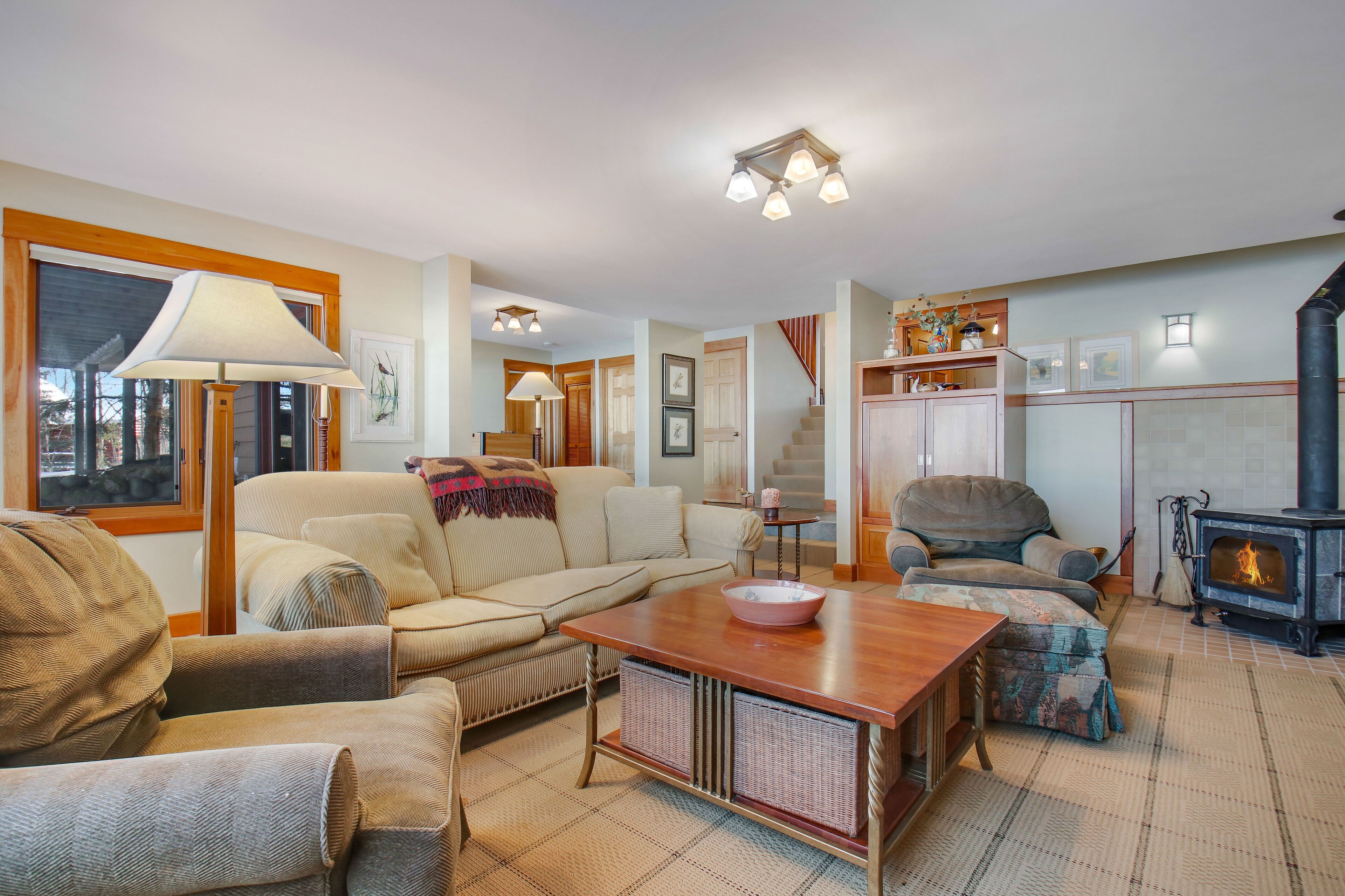 A cozy living room with a sofa, armchairs, a wooden coffee table, and a fireplace.