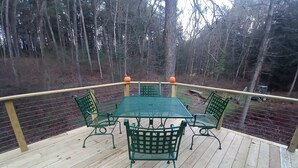 Een houten terras met een groene metalen tafel en stoelen, omgeven door een houten hekwerk.