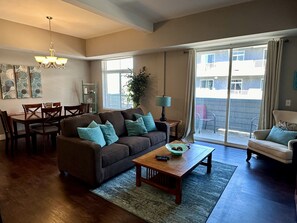 A living room with a sofa, coffee table, and dining area. - Updated Condo Near Beaches, Downtown, Restaurants, and Shops (Grand Haven)