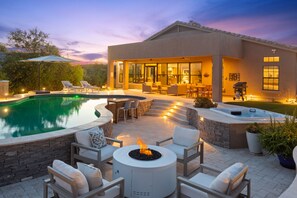 Un espacio exterior moderno con piscina, fogata y mobiliario para disfrutar al aire libre.