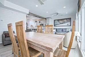 A modern dining area with a wooden table and chairs, a kitchen in the background, and a large map on the wall.