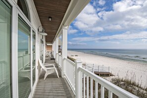 A beachfront property with a covered porch, white railings, and a view of the ocean. - Coastal Elegance Meets Family Comfort – Your Beach Stop Summer Escape (Gulf Shores)