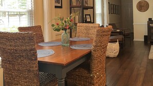 A dining area with a wooden table, wicker chairs, and a hanging light fixture. - Luxurious 2BR /2Bath with Outdoor Courtyard and Garage in Downtown Bardstown (Bardstown)