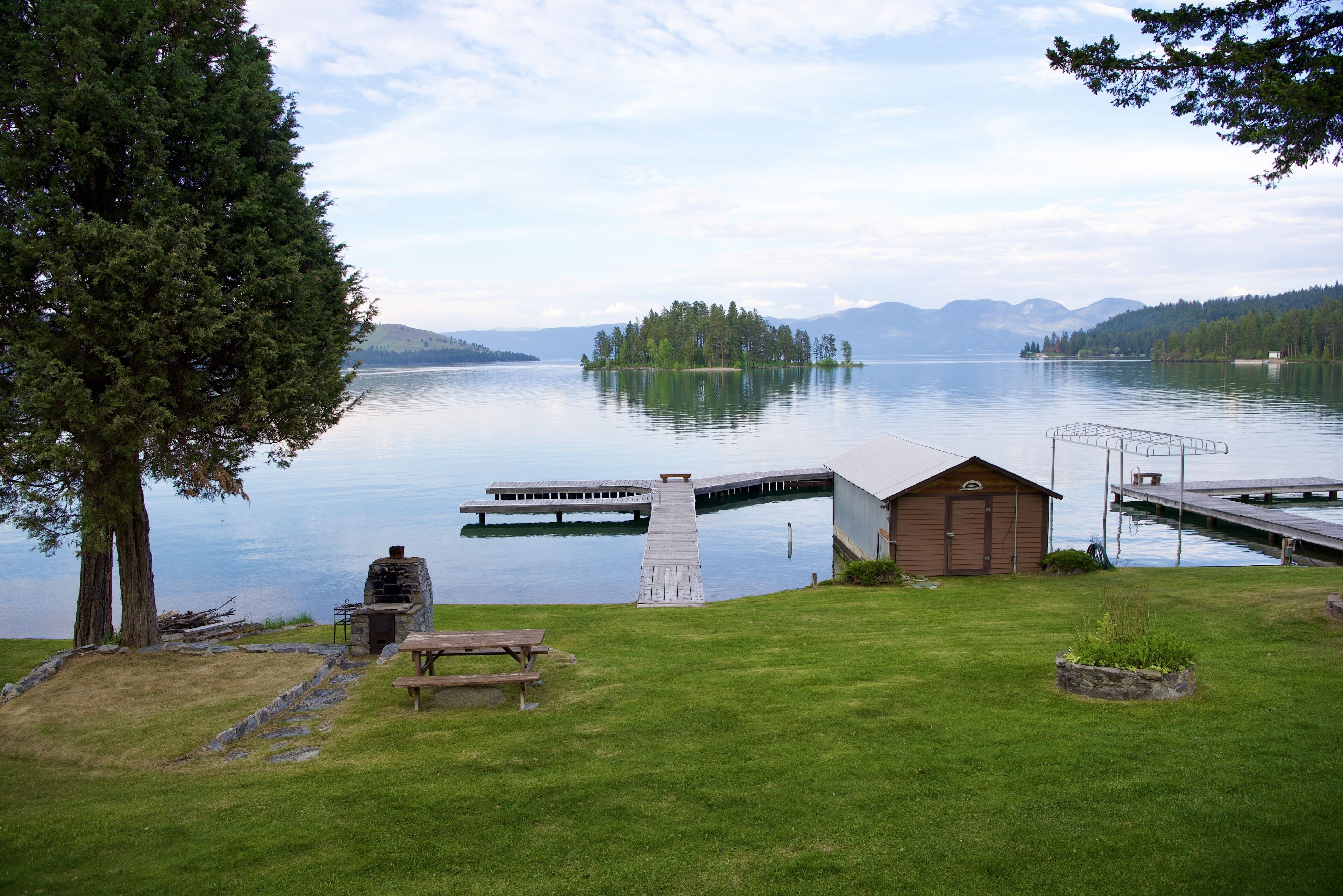 A lakeside property with a dock, picnic table, and a small building.