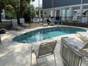 A swimming pool with safety signs, lounge chairs, and a covered area with a railing. - Oceanview at Surfside-Where the Fun is up and Stress is Down! (Myrtle Beach)