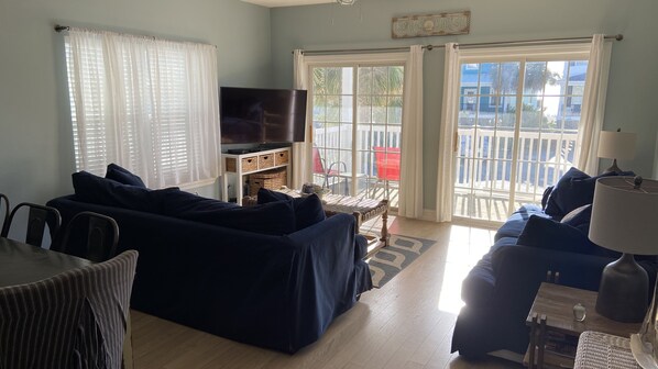 A living room with a dark blue sofa, a television, and a dining area with a table and chairs. - Oceanview at Surfside-Where the Fun is up and Stress is Down! (Myrtle Beach)