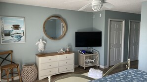 A bedroom with a bed, a dresser, a television, a mirror, and a door. - Oceanview at Surfside-Where the Fun is up and Stress is Down! (Myrtle Beach)