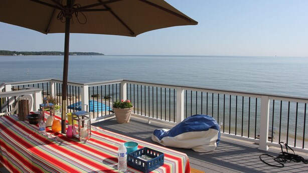A deck with a striped tablecloth, a blue basket, and a beige umbrella. - Beach Cottage With A Spectacular View ~ Your Own Private Beach ~ Includes Kayaks (Ridge)