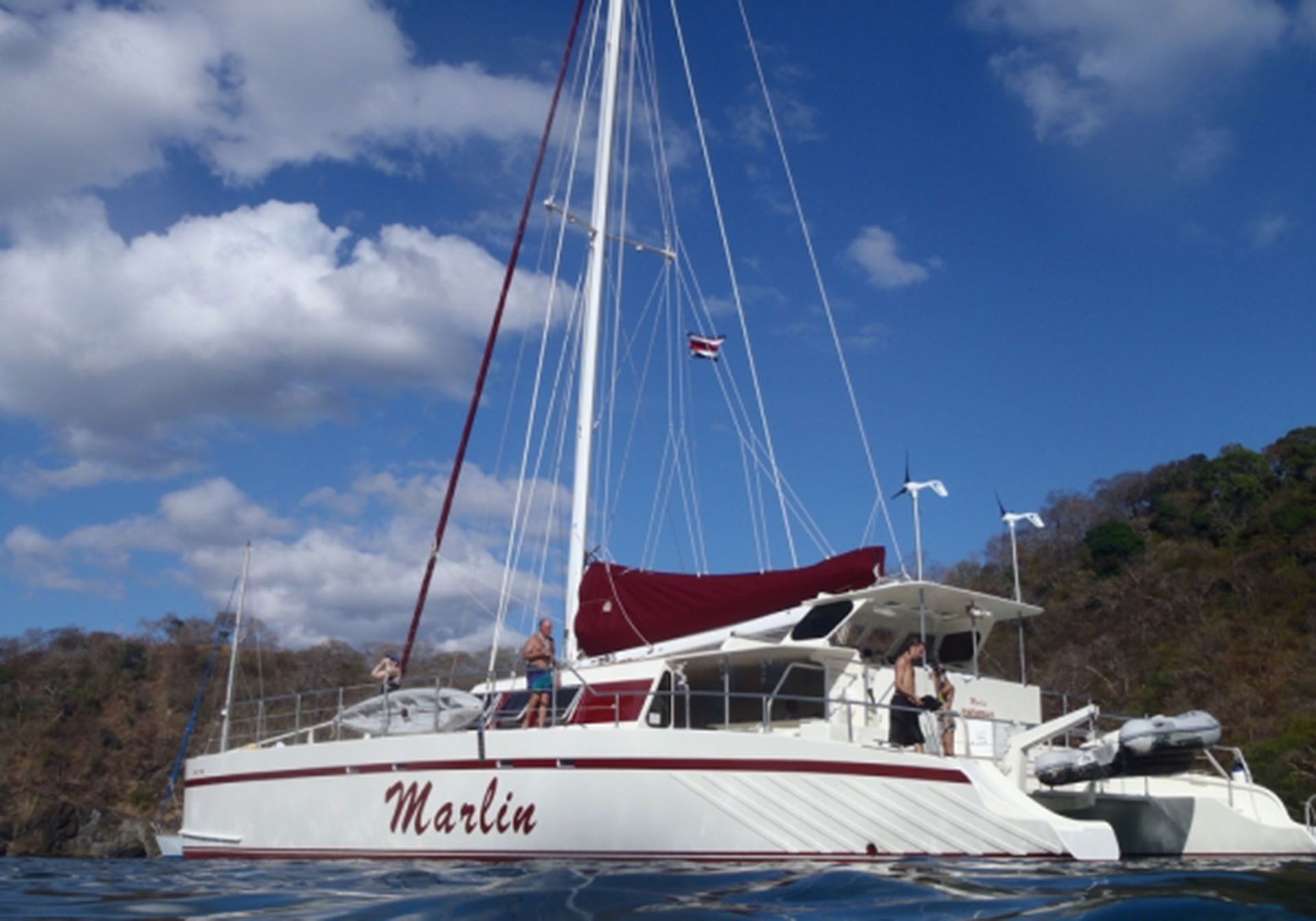 A white yacht named 'Marlin' with a red stripe, a cabin, and a flag.