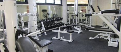 A gym with various exercise equipment, including dumbbells, benches, and weight machines.