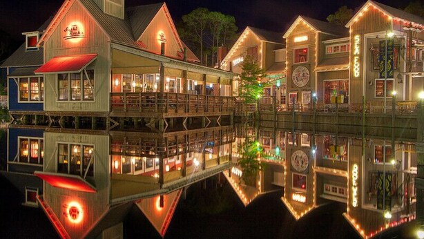 A waterfront building with multiple levels, including a docked boat, and a reflection in the water. - 1380 Laurel Grove 3 Bedroom Home by RedAwning (Miramar Beach)