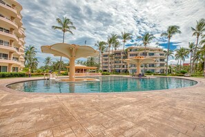Ein Poolbereich eines Resorts mit Palmen und einem großen Gebäude im Hintergrund.